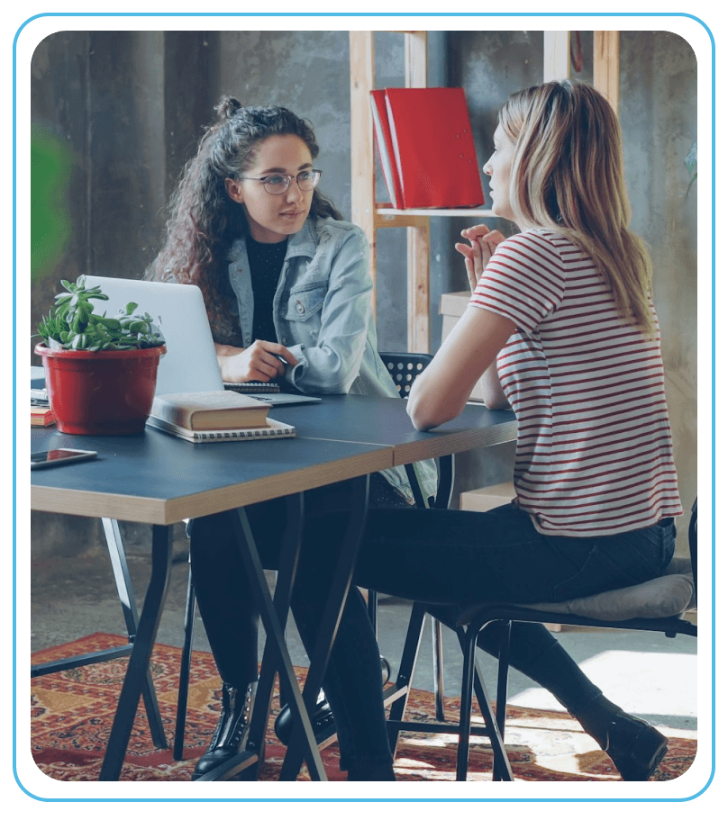 Two women sitting together at table in modern office
